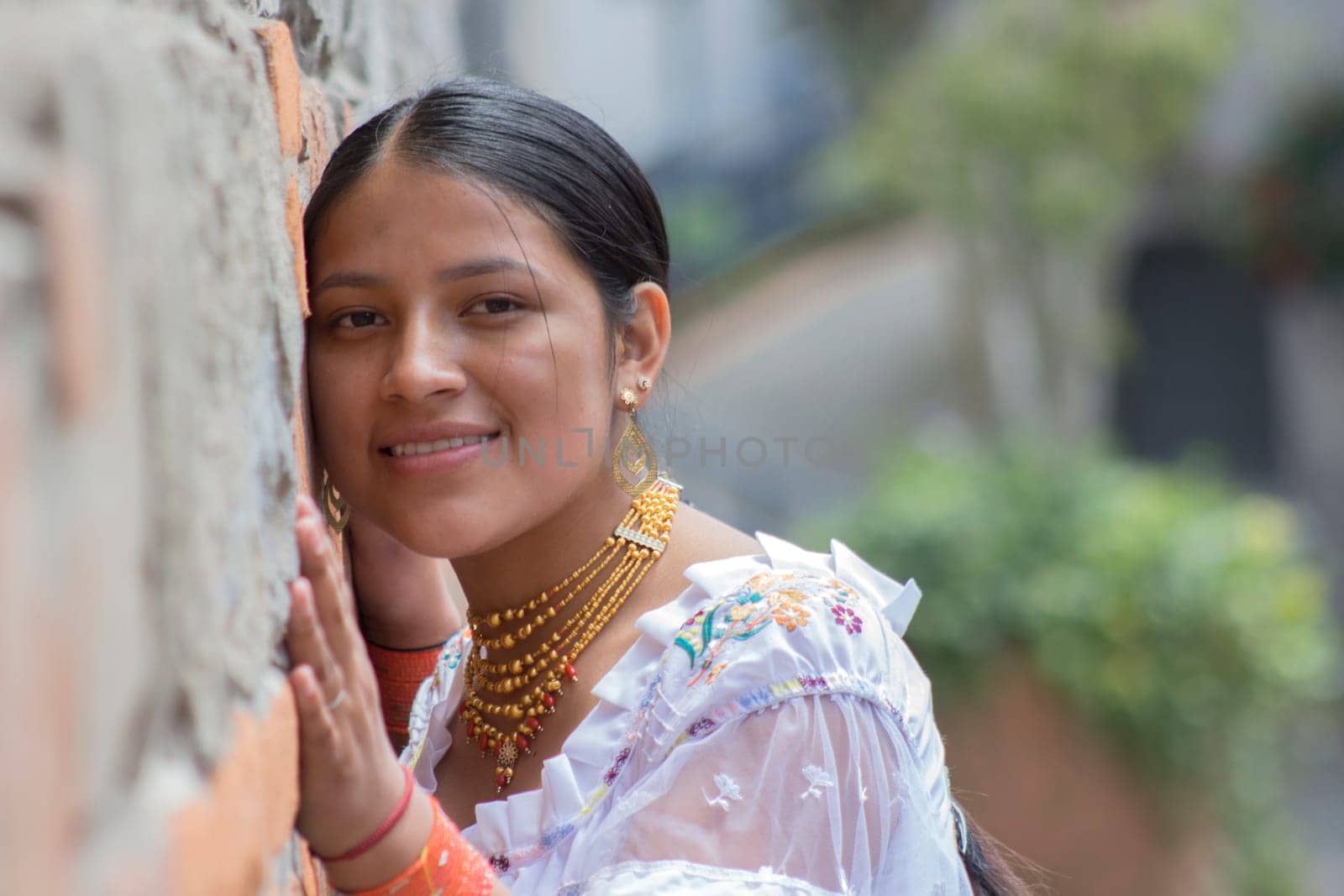 Pretty and young indigenous woman smiling at the camera in traditional dress of her culture in a park. High quality photo