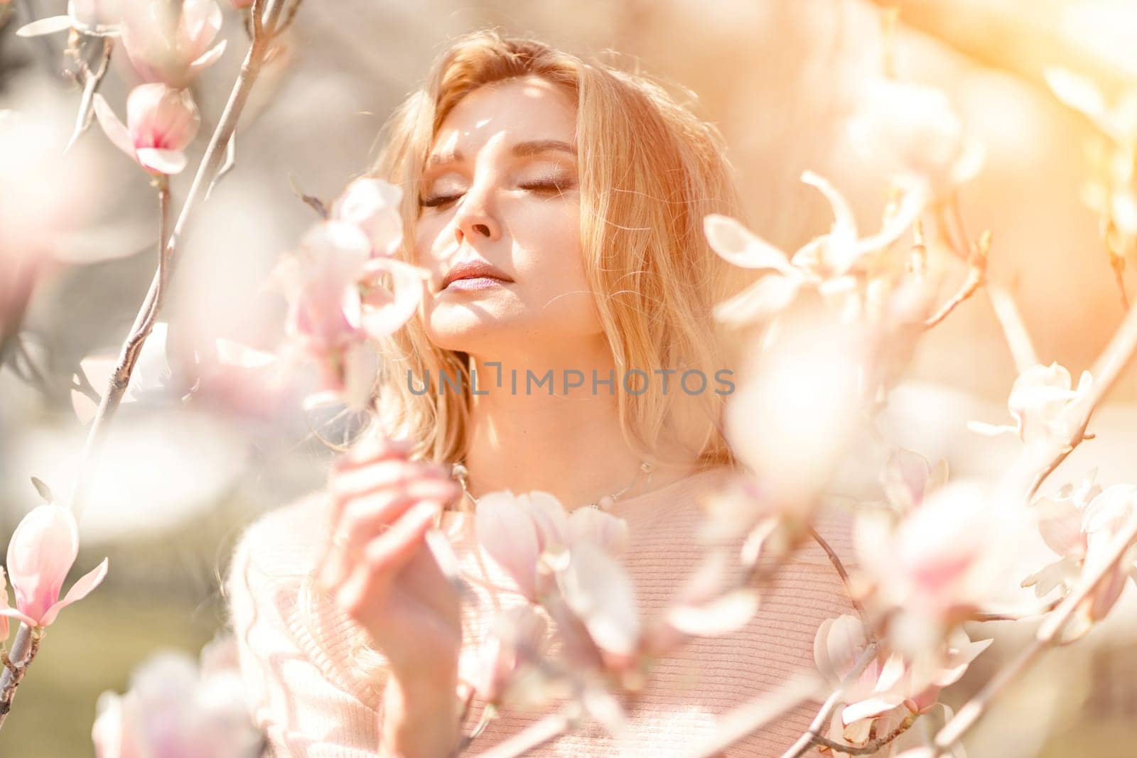 Magnolia woman portrait. Happy middle aged woman enjoying the smell in a blooming spring garden. Beautiful magnolia bushes, large flowers