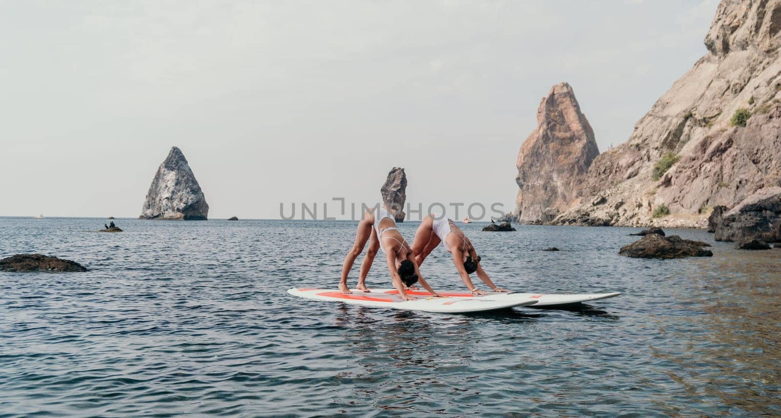 Woman sup yoga. Middle age sporty woman practising yoga pilates on paddle sup surfboard. Female stretching doing workout on sea water. Modern individual hipster outdoor summer sport activity