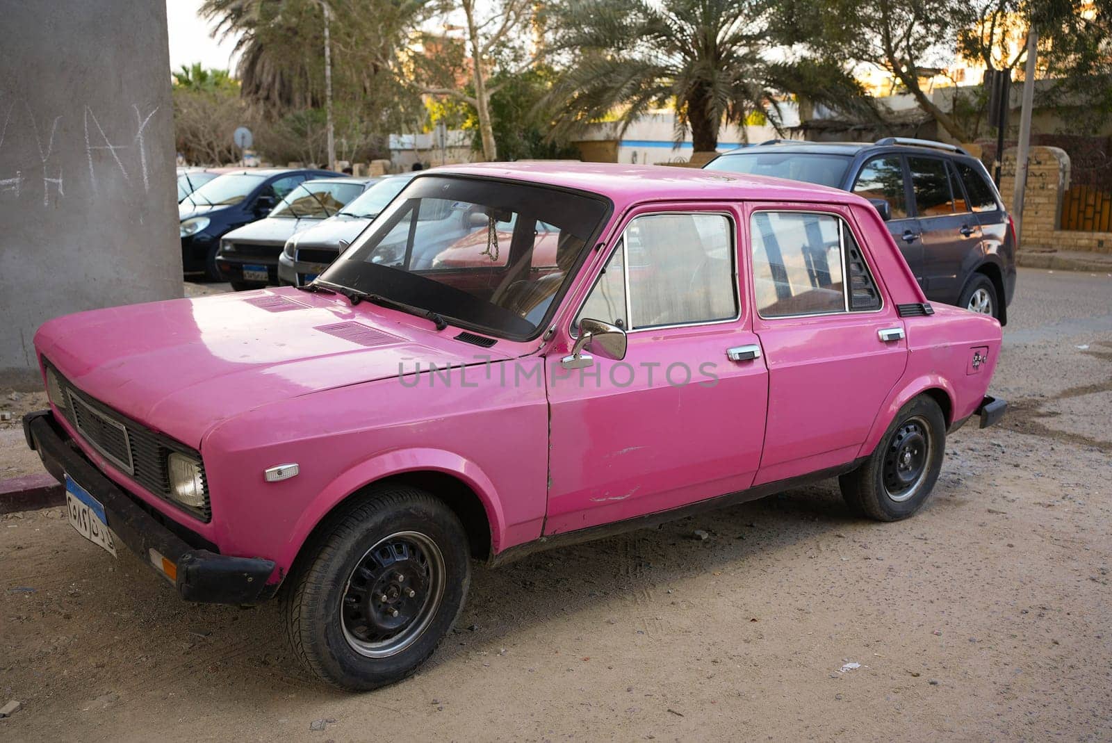 Old pink car parking in a street. High quality photo
