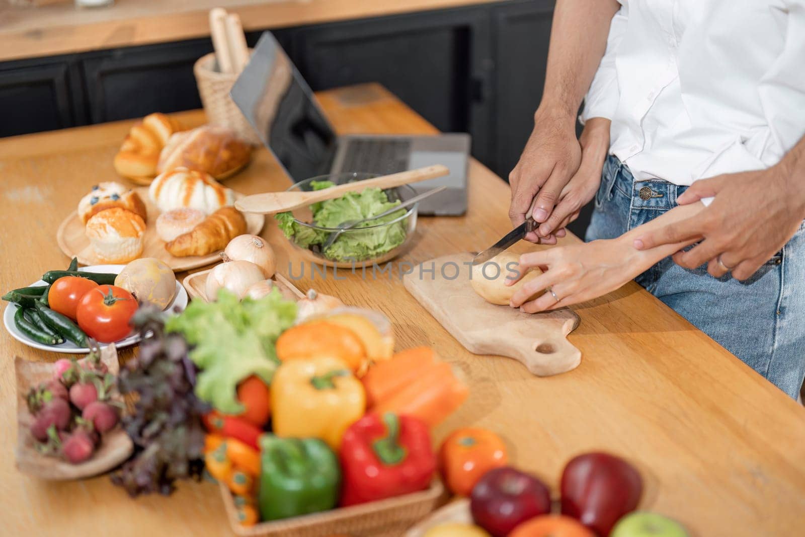 couple cutting vegetable during cooking salad at home kitchen. and healthy eating. Idea of relationship and enjoying time together. Smiling young man and woman by nateemee