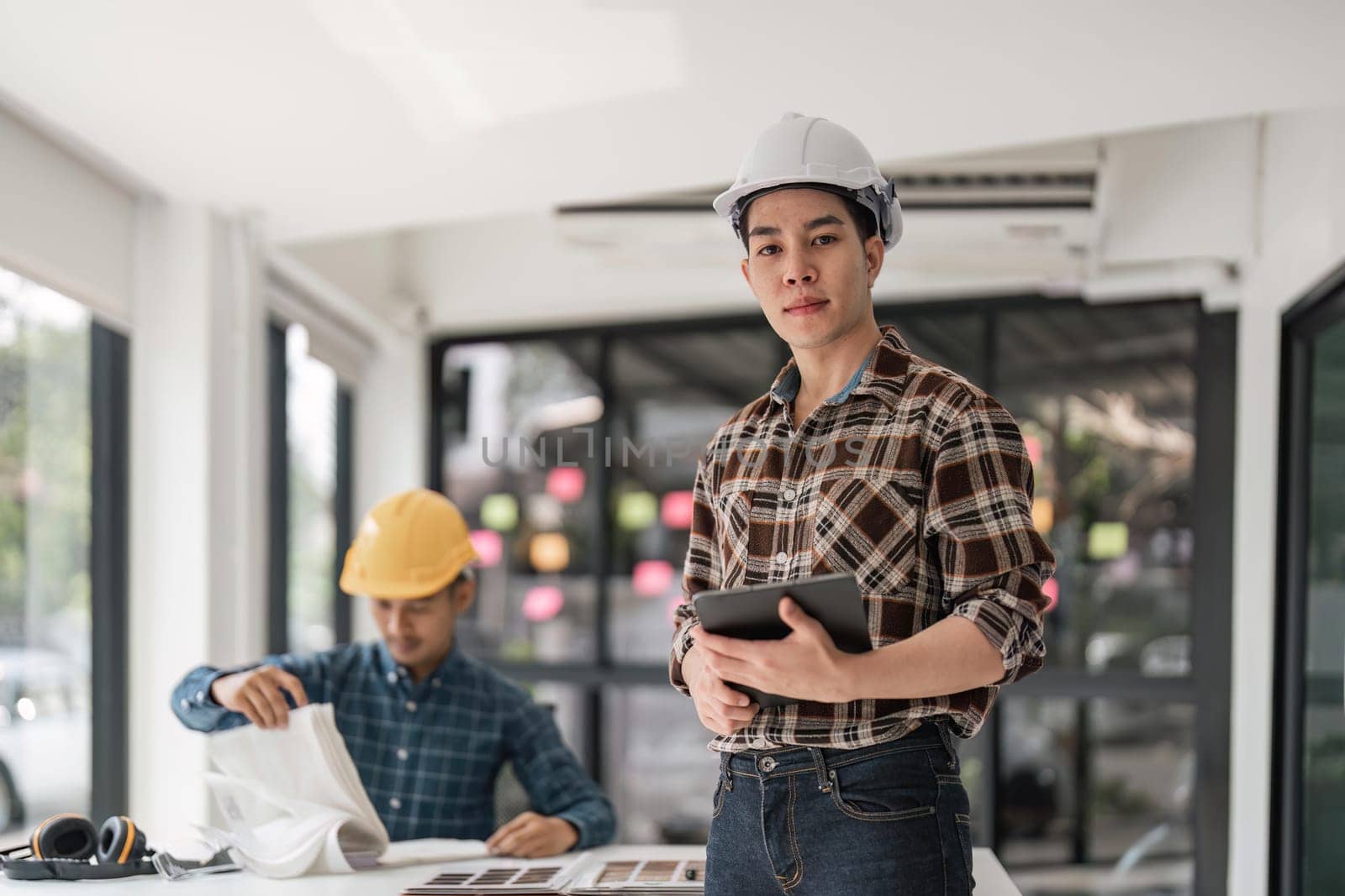 Portrait of engineer with tablet in creative office. contractor holding tablet in architectural projects while looking at camera. Happy asia man in casual.