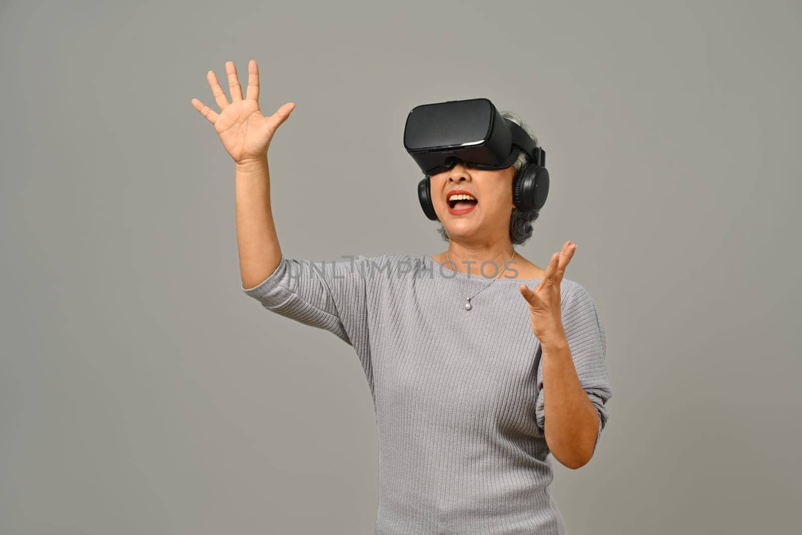Portrait of amazed senior woman VR headset enjoying virtual reality experience. Modern technologies, innovations and gadgets.