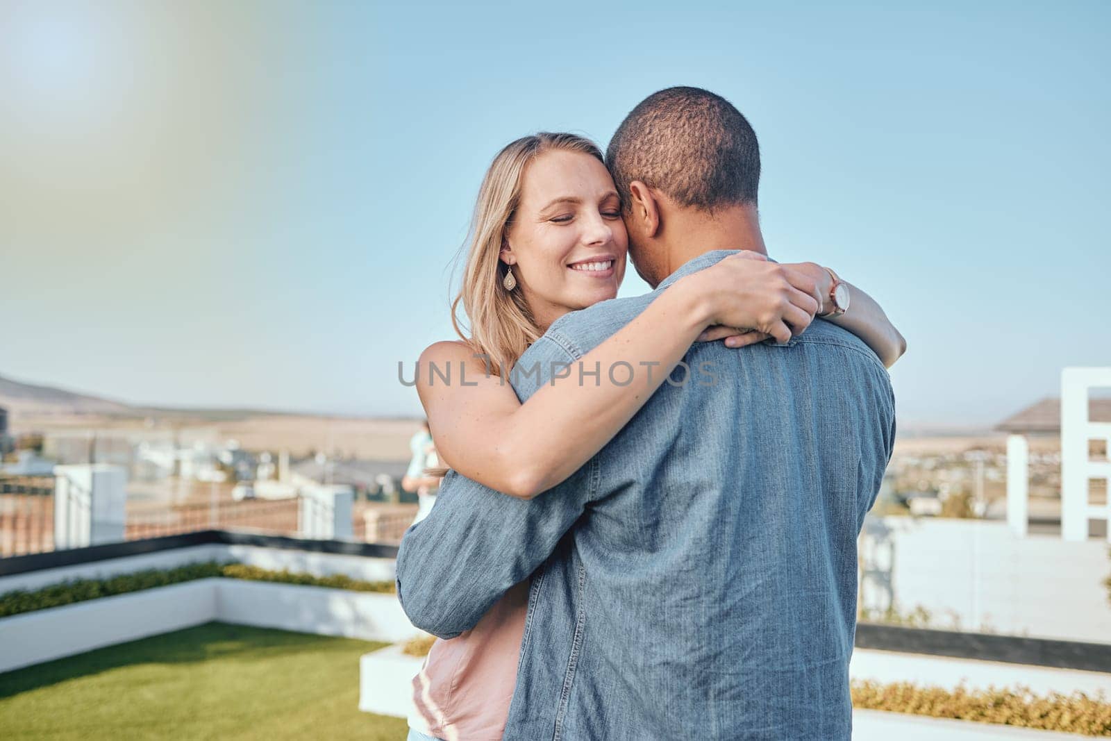 Couple, love and hug on city building rooftop for date, romance and quality time while dancing and happy together. Interracial man and woman on vacation in Cape town in summer for cityscape travel.