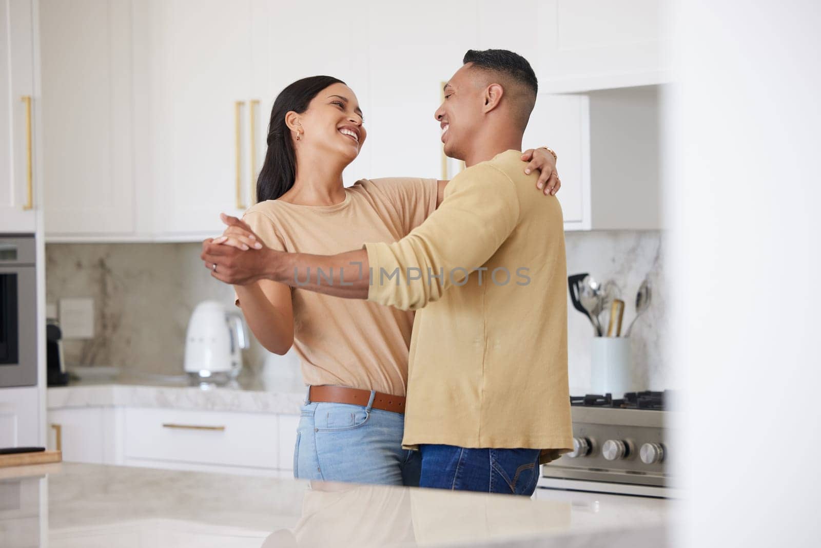 Love, smile and couple dance in kitchen, celebrating anniversary and bonding. Happy, man and woman dancing, romance and affection, carefree or playful people having fun spending time together in home by YuriArcurs