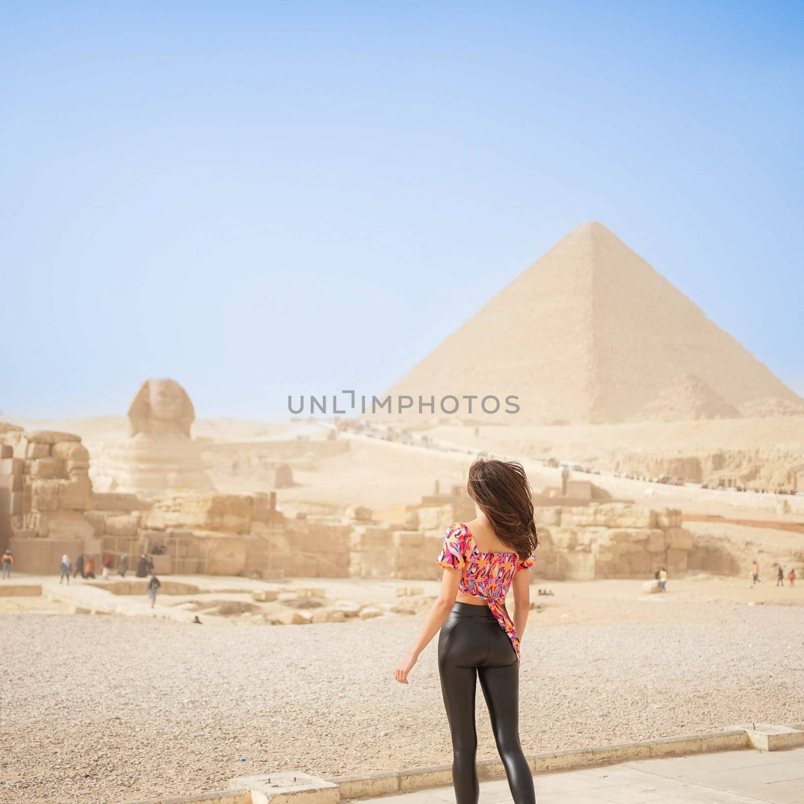 Beautiful Girl standing in front of the Pyramid of Giza and the Sphynx. High quality photo