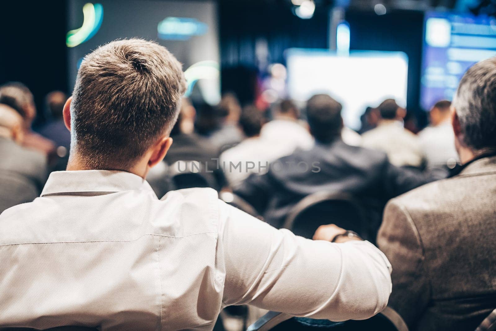 Speaker giving a talk in conference hall at business event. Rear view of unrecognizable people in audience at the conference hall. Business and entrepreneurship concept