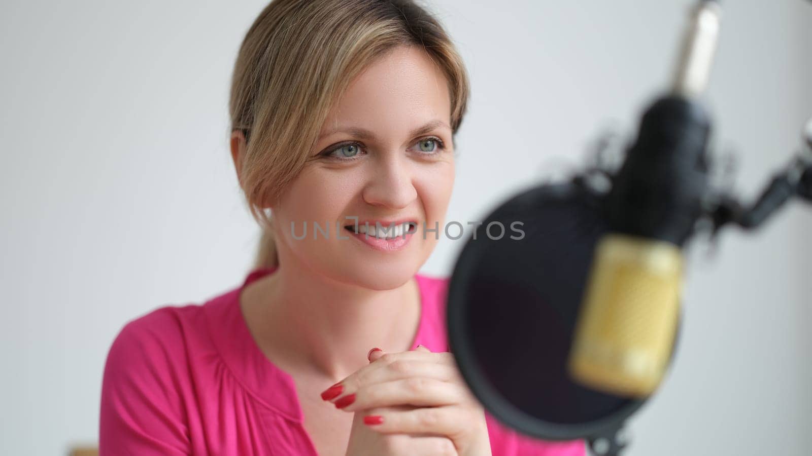 Woman radio presenter speaking into microphone in recording studio. Work on radio concept