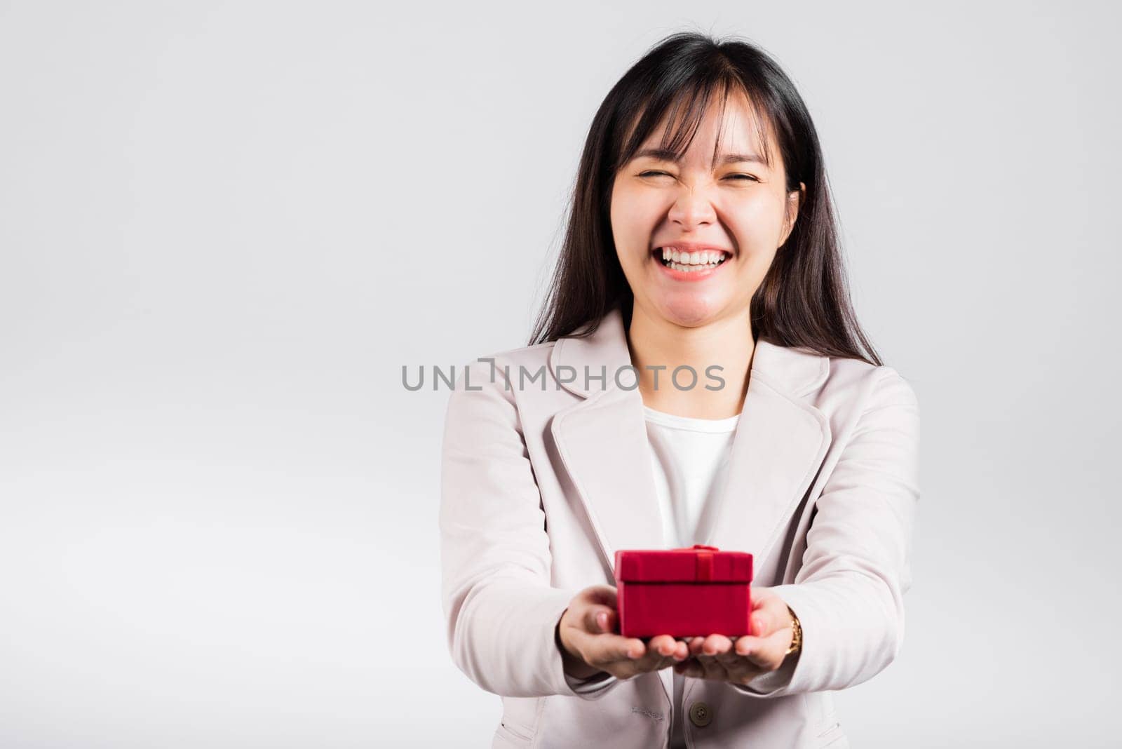 Smiling woman confidence holding red gift box on hands palm isolated white background, surprise birthday or Christmas day and valentine, Asian happy portrait beautiful female studio shot, copy space