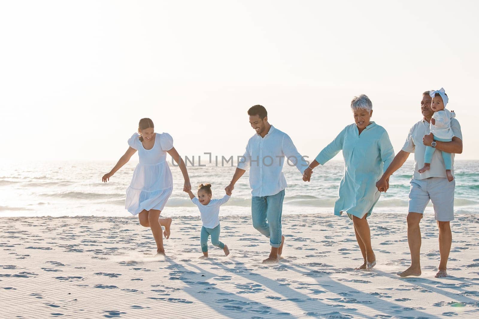 Big family, holding hands and walking on beach for holiday weekend or vacation with mockup space. Grandparents, parents and kids on a ocean walk together for fun bonding or quality time in nature.