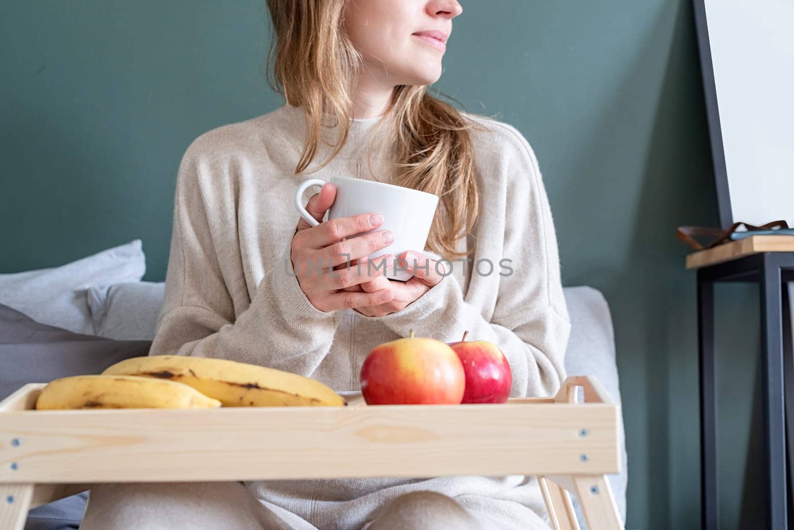 Woman sitting at bed at home drinking coffee by Desperada