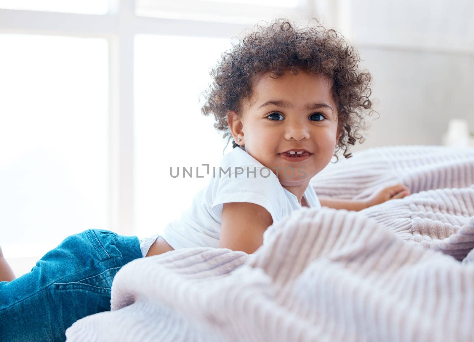 Portrait, toddler girl and smile in bedroom for happiness, childhood development and growth with curly hair. Cute, adorable and sweet young child, happy kid and relax in comfortable nursery at home.