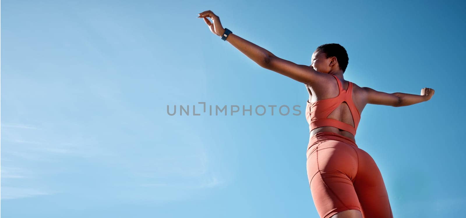Woman, arms up or fitness success on blue sky background in workout, training or exercise goals for healthcare or cardiovascular wellness. Low angle runner, sports athlete or hands raised with mockup.