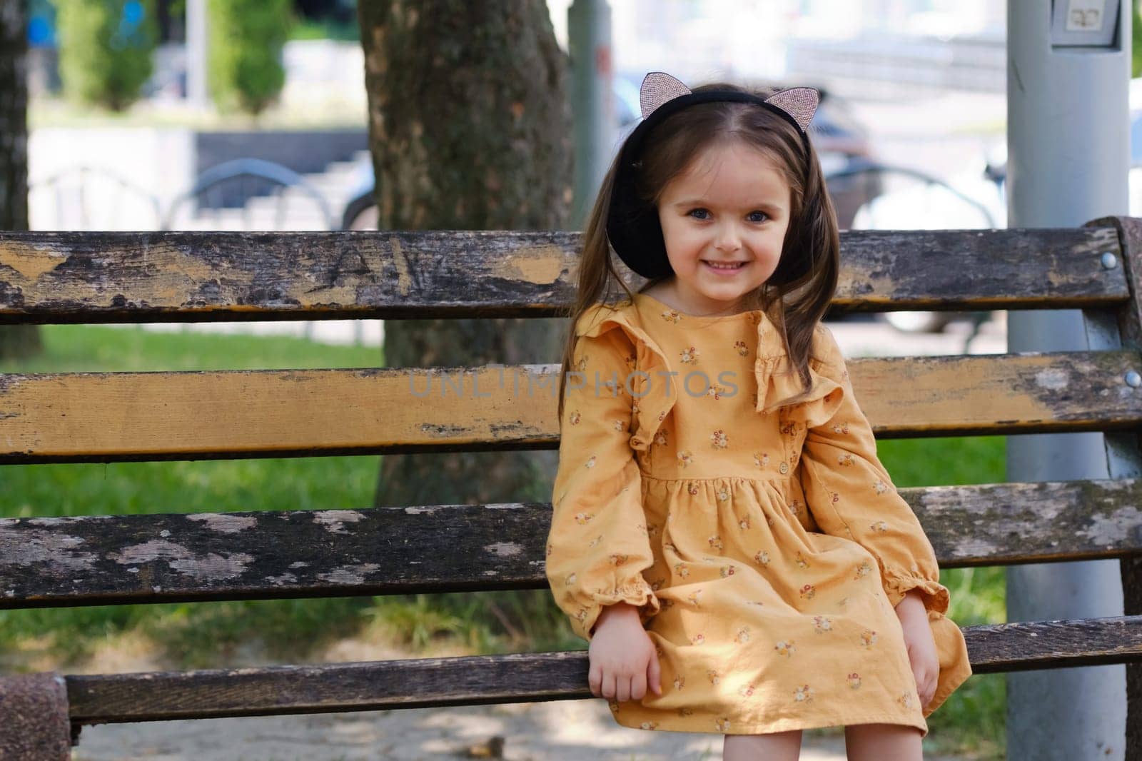 Portrait of a four-year-old girl sitting on a park bench.