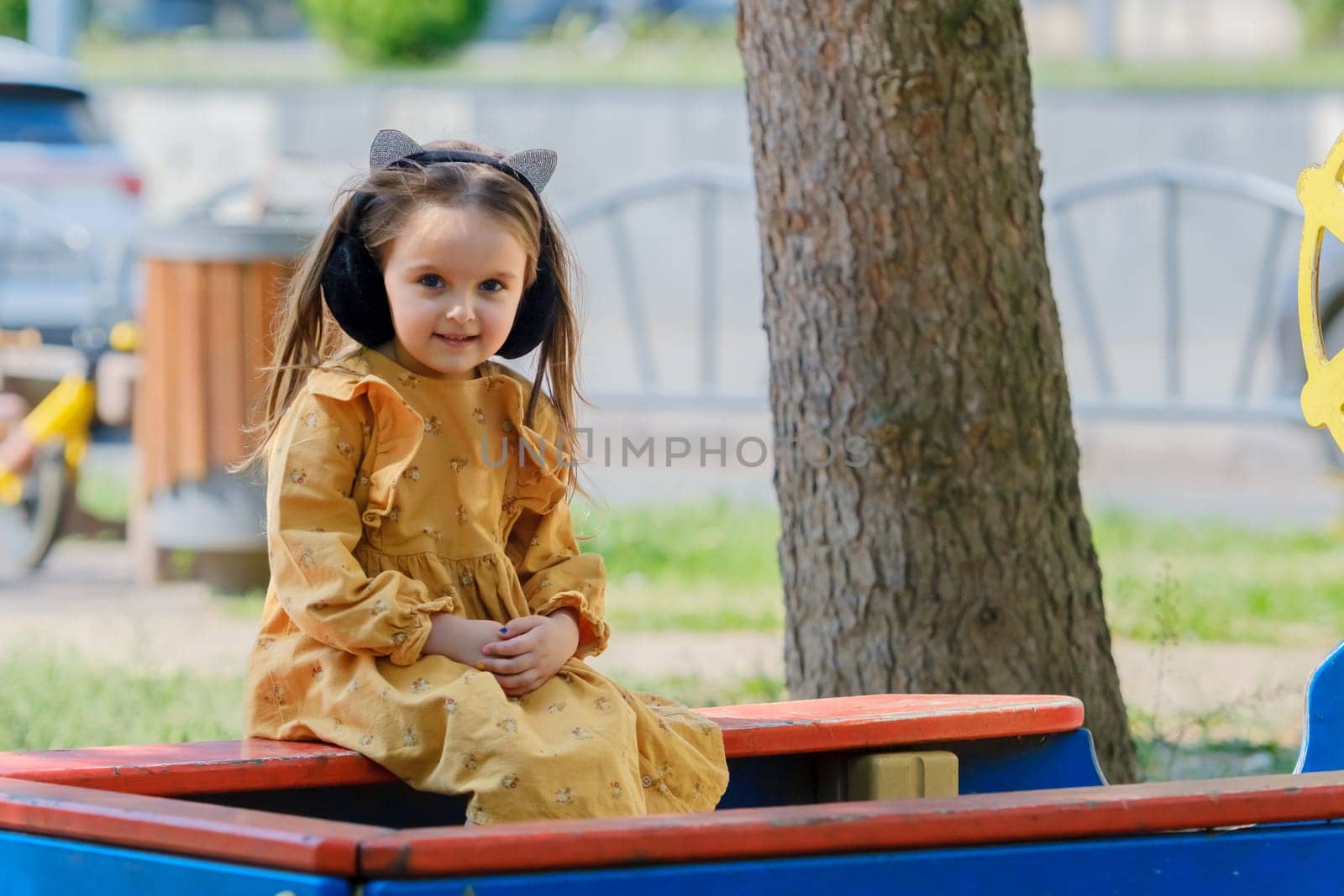 Portrait of a four-year-old girl sitting on a park bench.