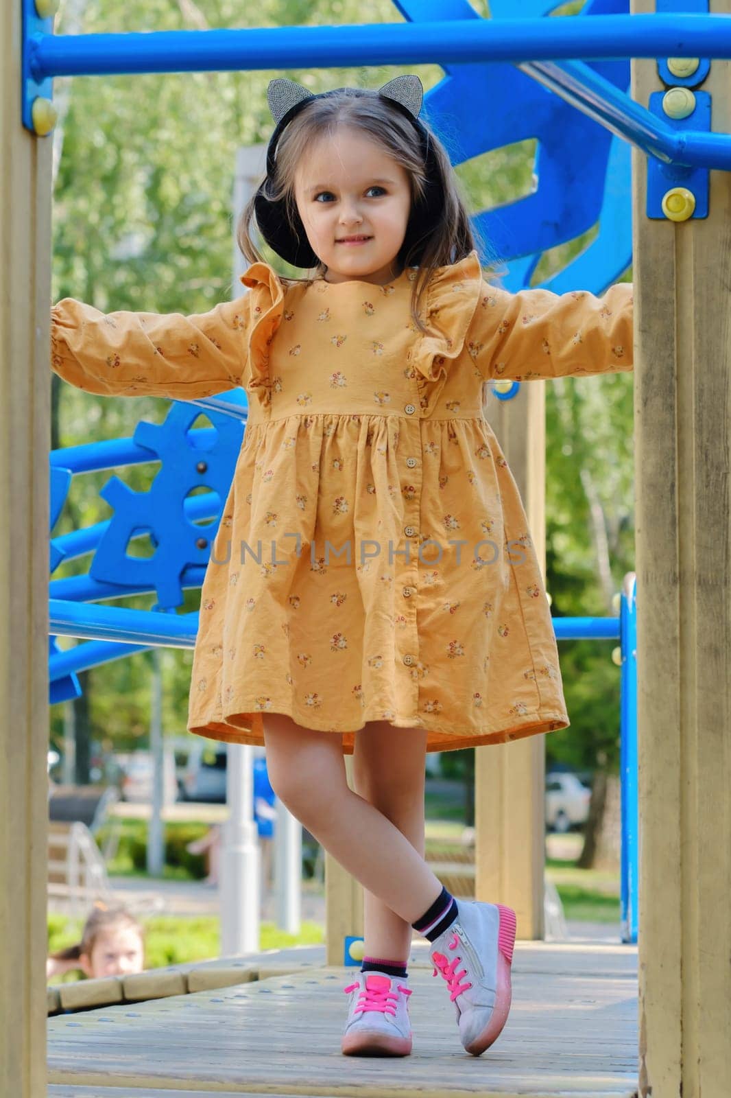 Happy little girl is playing on the playground in the park.