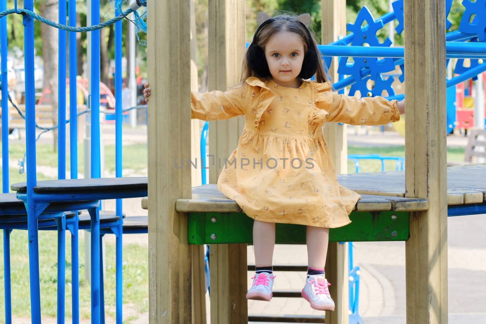 Happy little girl is playing on the playground in the park.