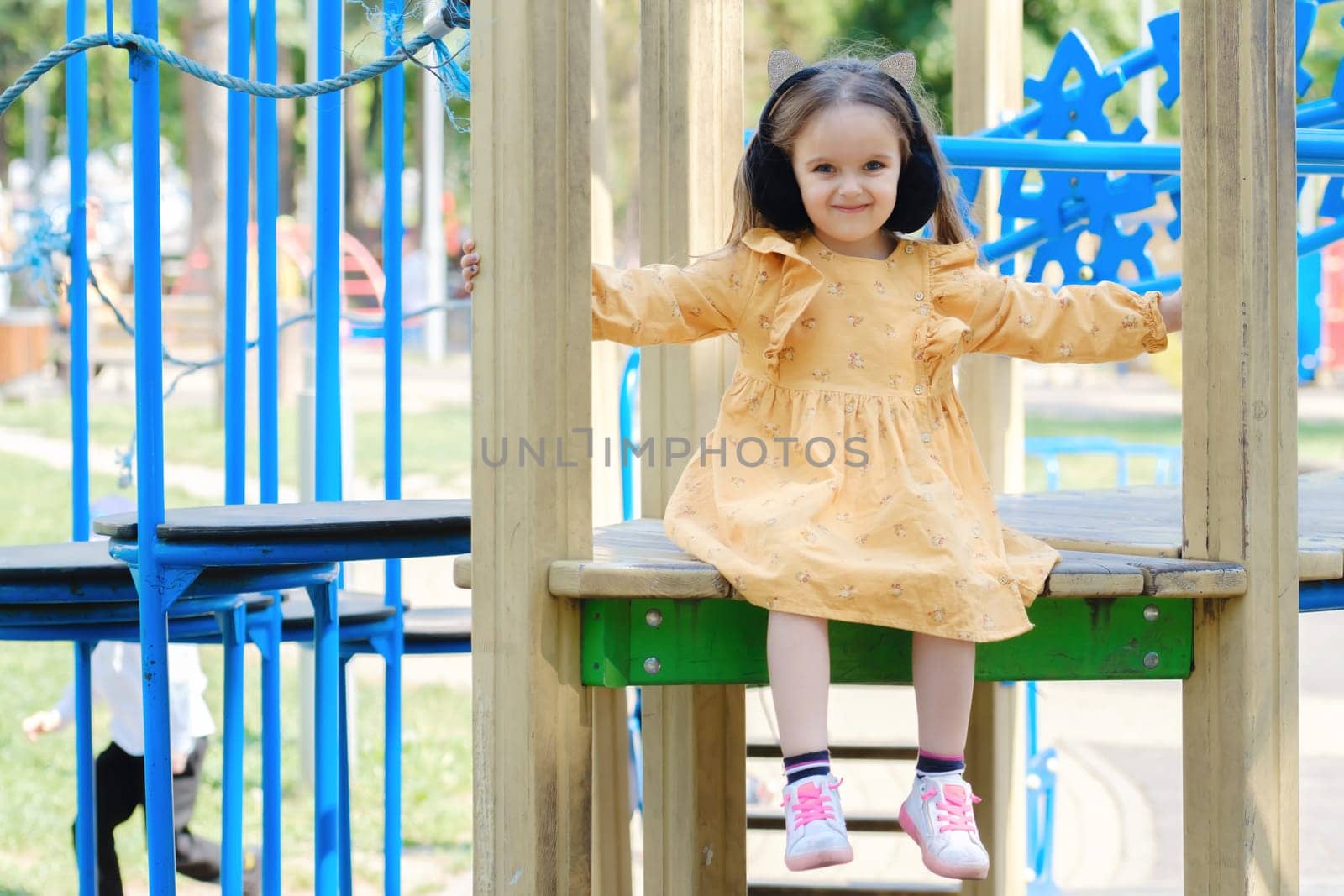 Happy little girl is playing on the playground in the park.