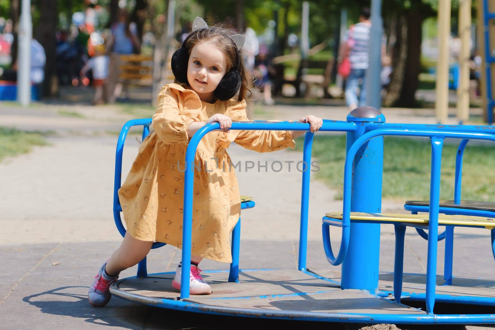 Happy little girl is playing on the playground in the park.