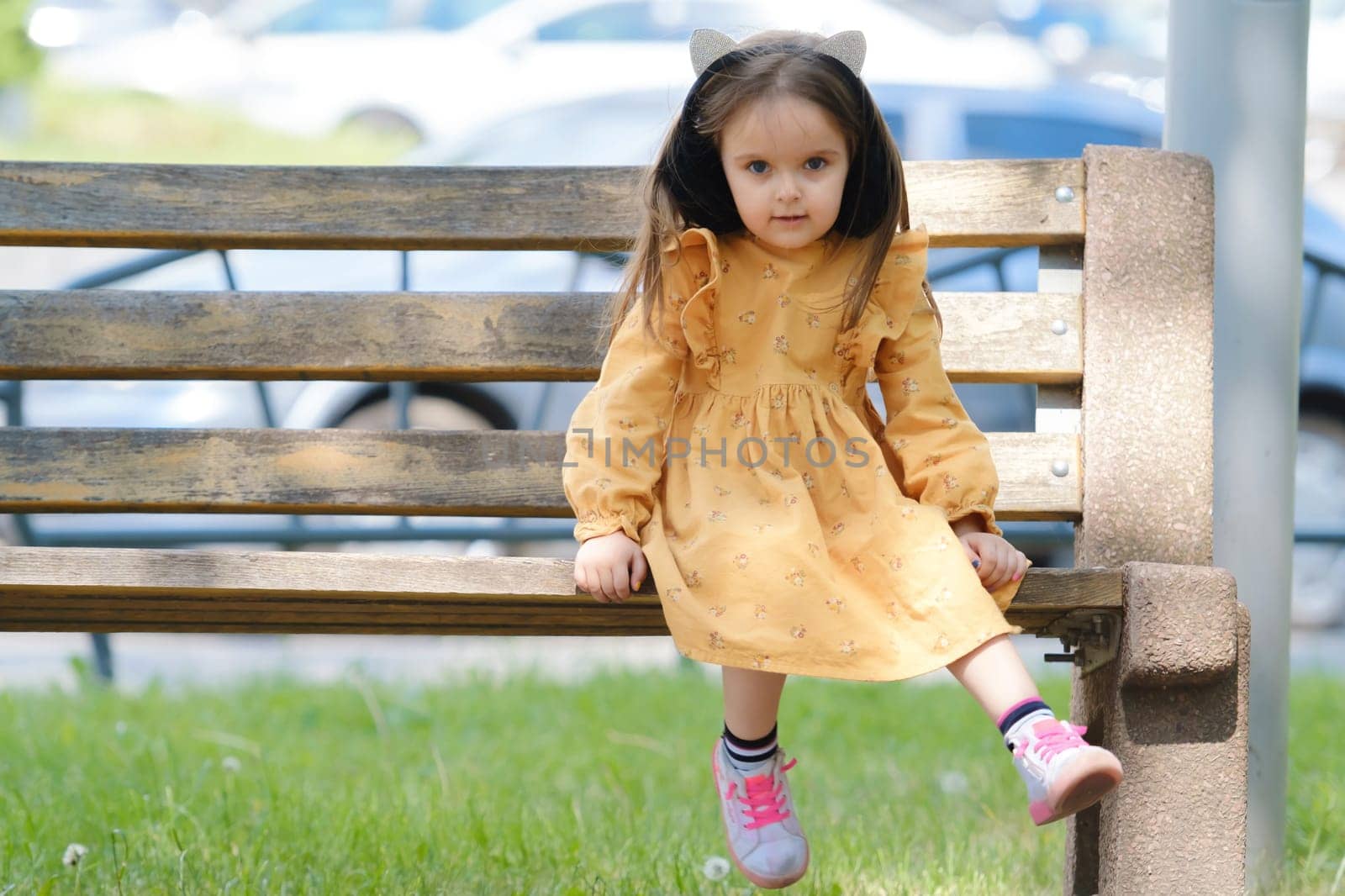 Portrait of a four-year-old girl sitting on a park bench. by leonik