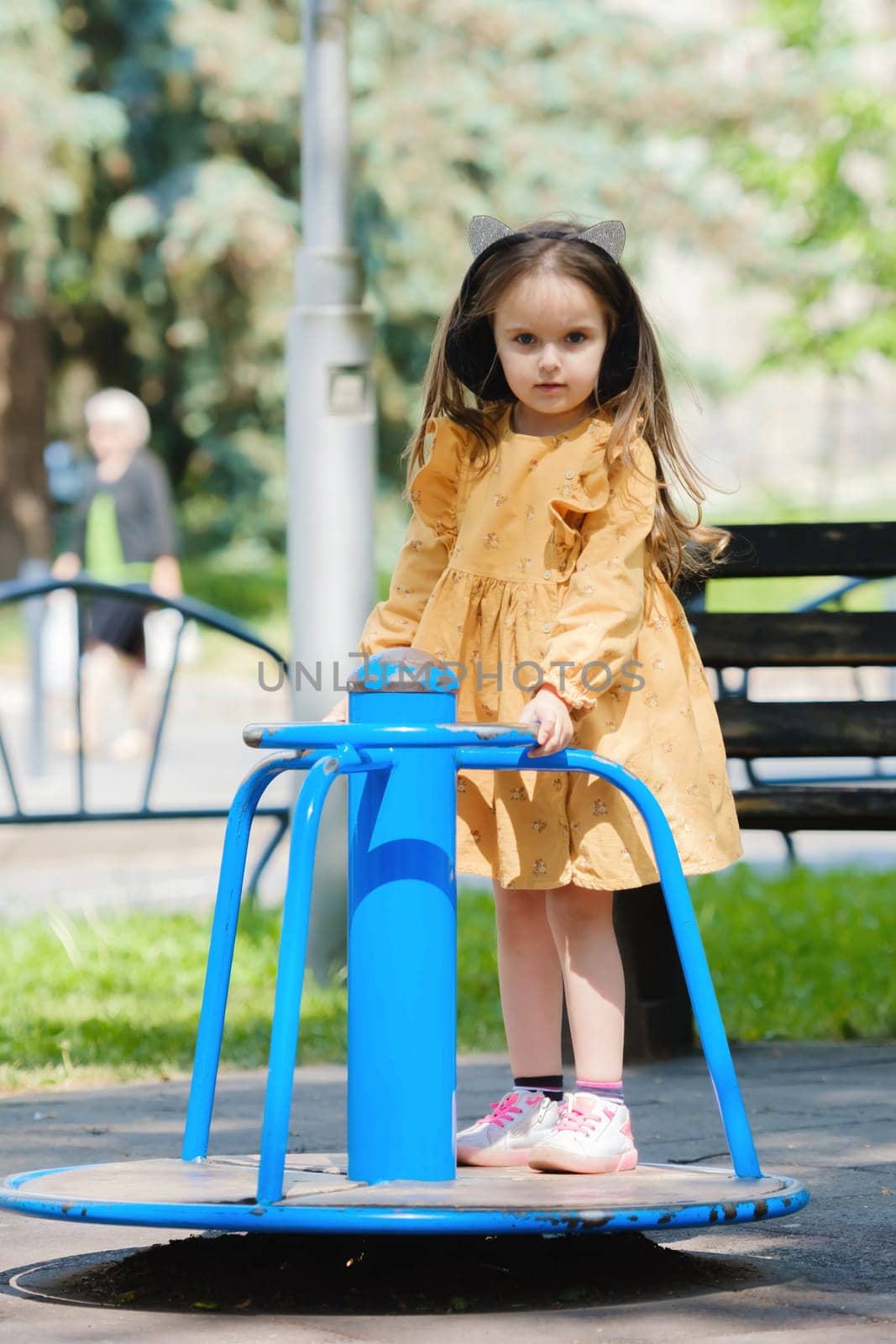 Happy little girl is playing on the playground in the park.