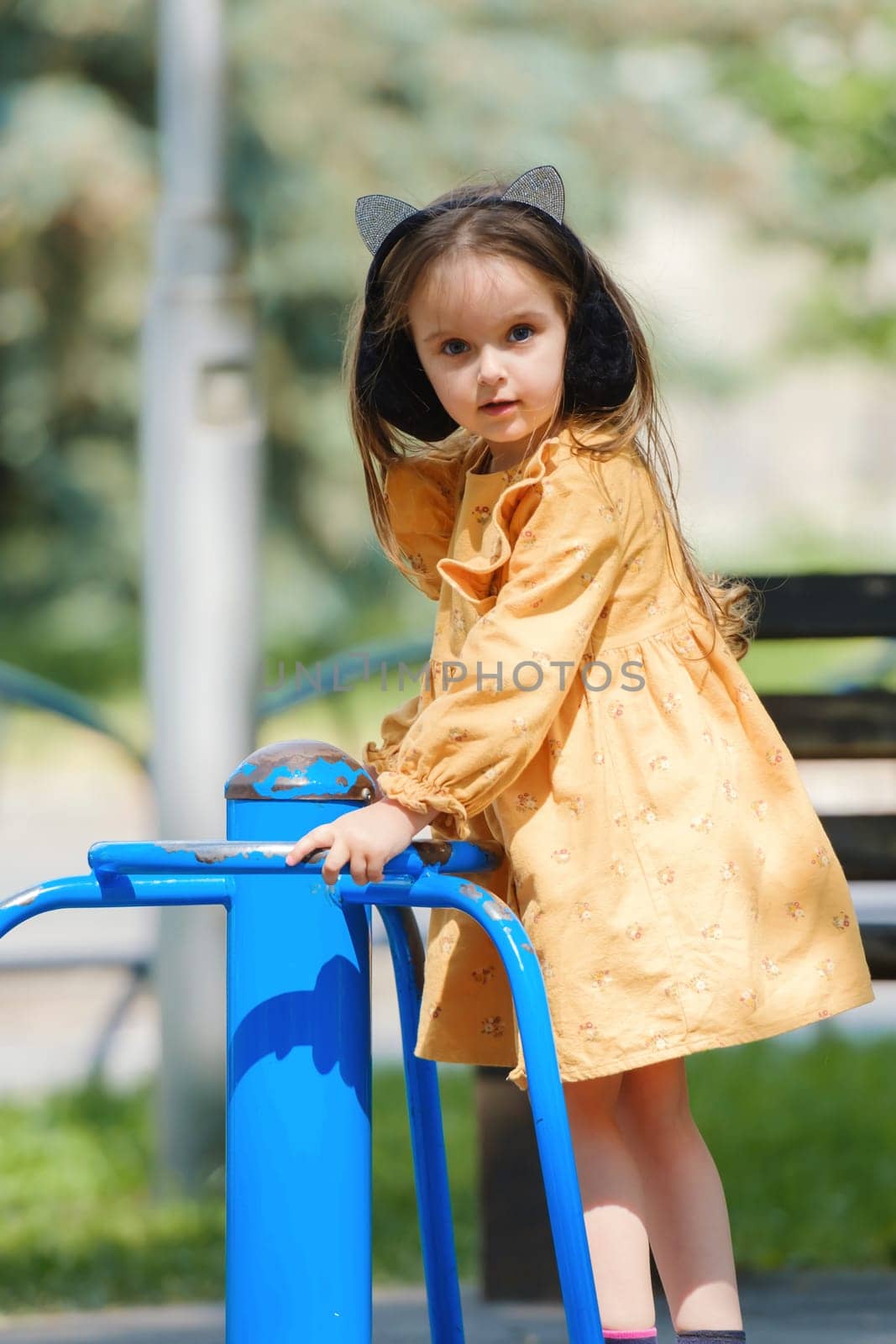 Happy little girl is playing on the playground in the park.