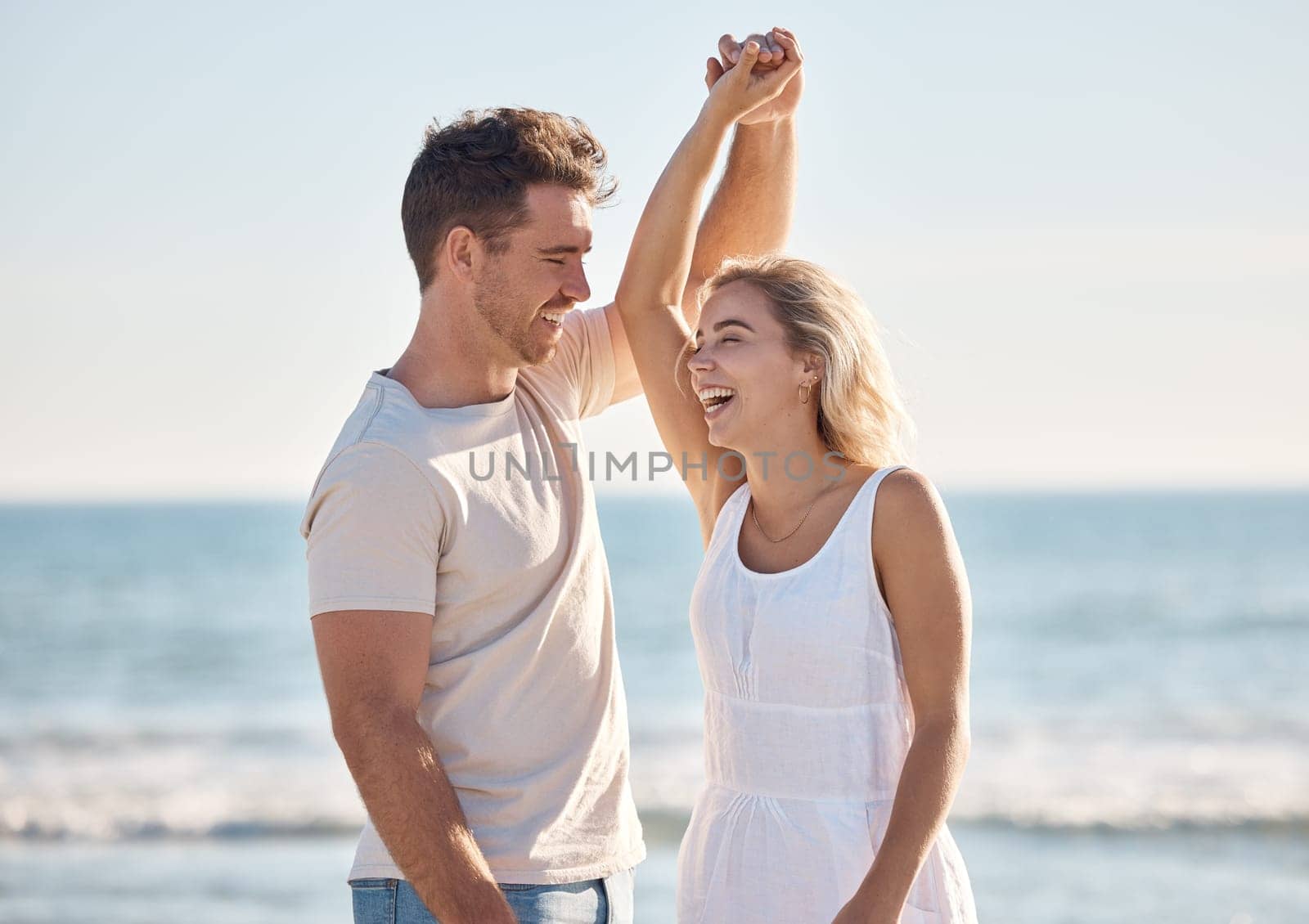 Beach, love and dance with a young couple in nature, happy together during a date or summer vacation. Smile, travel and romance with a man and woman dancing by the sea or ocean while bonding by YuriArcurs