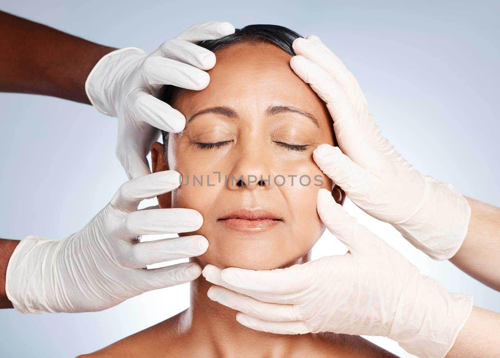 Cosmetics, plastic surgery and hands check woman face for laser, botox implant or beauty salon. Skincare consultation, facial or gloves of aesthetic change, liposuction or filler on studio background by YuriArcurs