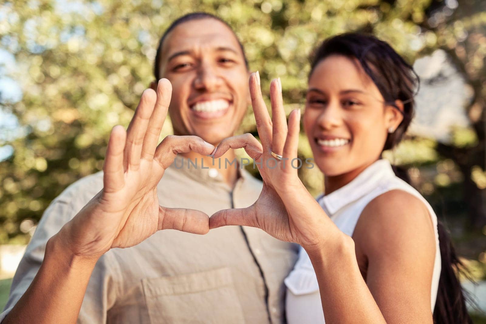 Hands, heart and love with a black couple sign outdoor in the garden of their home together. Happy, hand and romance with a man and woman making a shape with their fingers while bonding outside.