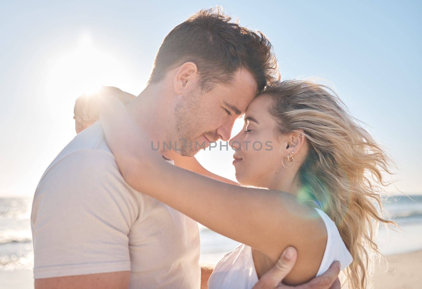 Love, travel and couple hugging at the beach while on a seaside date or honeymoon vacation. Affection, romance and young man and woman embracing while on a romantic holiday adventure by the ocean