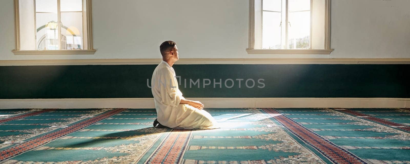 Mosque, worship and muslim man in prayer on his knees for gratitude, support or ramadan for spiritual wellness. Religion, tradition and islamic guy praying or reciting quran to allah at islam temple