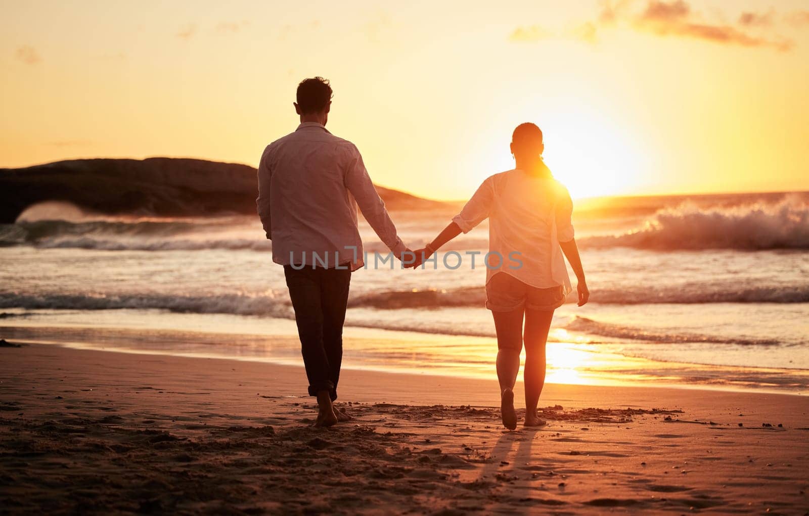 Sunset, couple holding hands and walking by the beach with a beautiful twilight. Love, romance and happy man and woman spending time together with affection by ocean, sea and sandy shore on holiday. by YuriArcurs