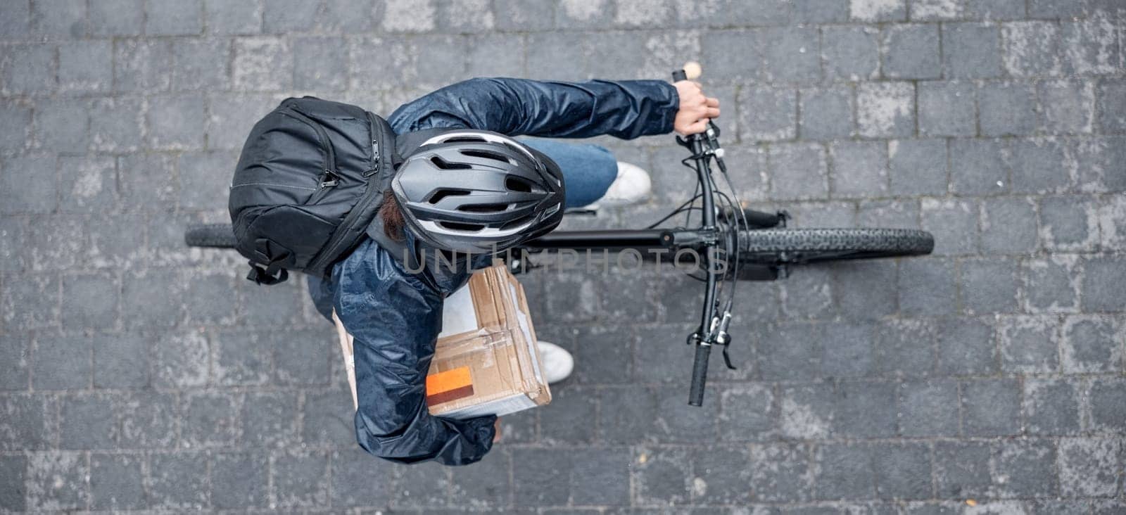 Top view, bicycle and delivery man with box in city for package, logistics and shipping. Courier, eco friendly transport and male bike driver with cargo, stock or goods for ecommerce on road in town. by YuriArcurs