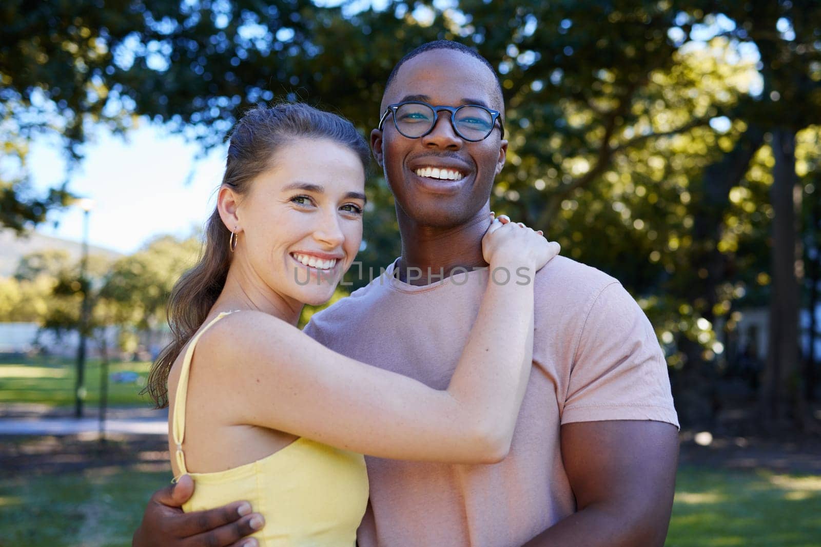 Interracial, portrait and couple hug, park or smile for relationship, romance or bonding. Love, black man or woman romantic in nature, loving or happiness with embrace, dating or quality time outdoor.