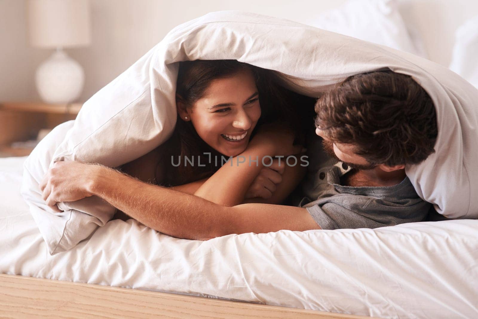 Blanket, smile and couple with love, home and peace with happiness, romance and loving together. Partners, man and woman in the bedroom, peace and romantic with peace, laughing and bonding at home.