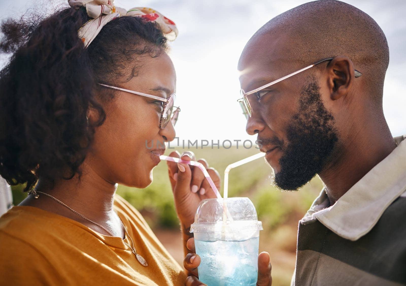 Love, share and drink with straw and couple in nature for travel, countryside and sunset date on Madrid vacation. Happy, summer and romance with black man and woman drinking together on holiday.