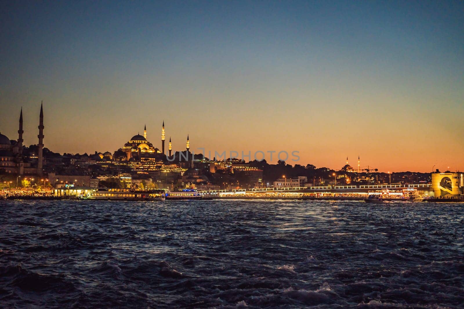 Istanbul at sunset, Turkey. Tourist boat sails on Golden Horn in summer. Beautiful sunny view of Istanbul waterfront with old mosque. Concept of travel, tourism and vacation in Istanbul and Turkey. Turkiye by galitskaya