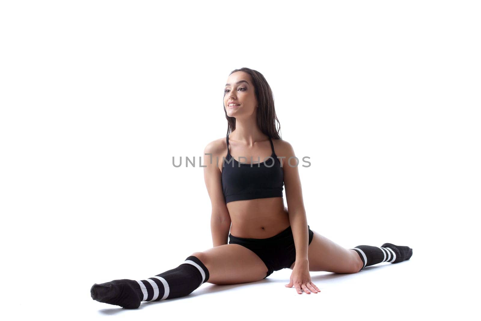 Attractive smiling model posing sitting on split, isolated over white background