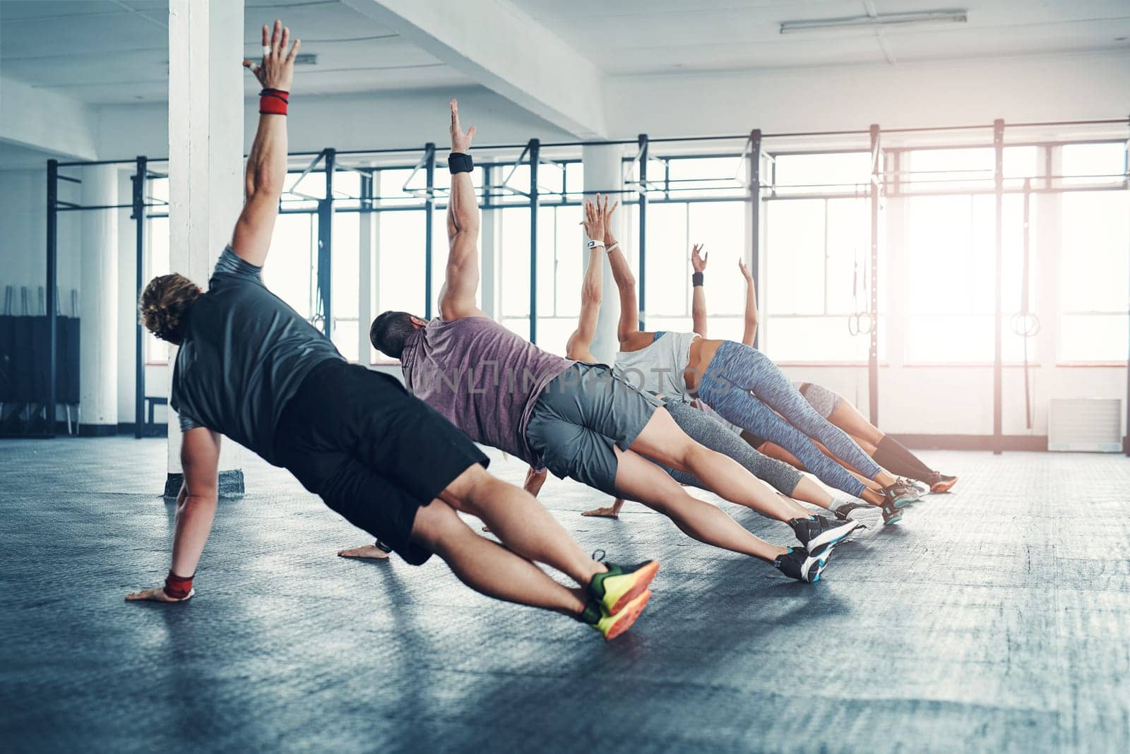 Fitness, group class and athletes doing a exercise in the gym for health, wellness and flexibility. Sports, training and people doing side plank exercise challenge together in sport studio or center
