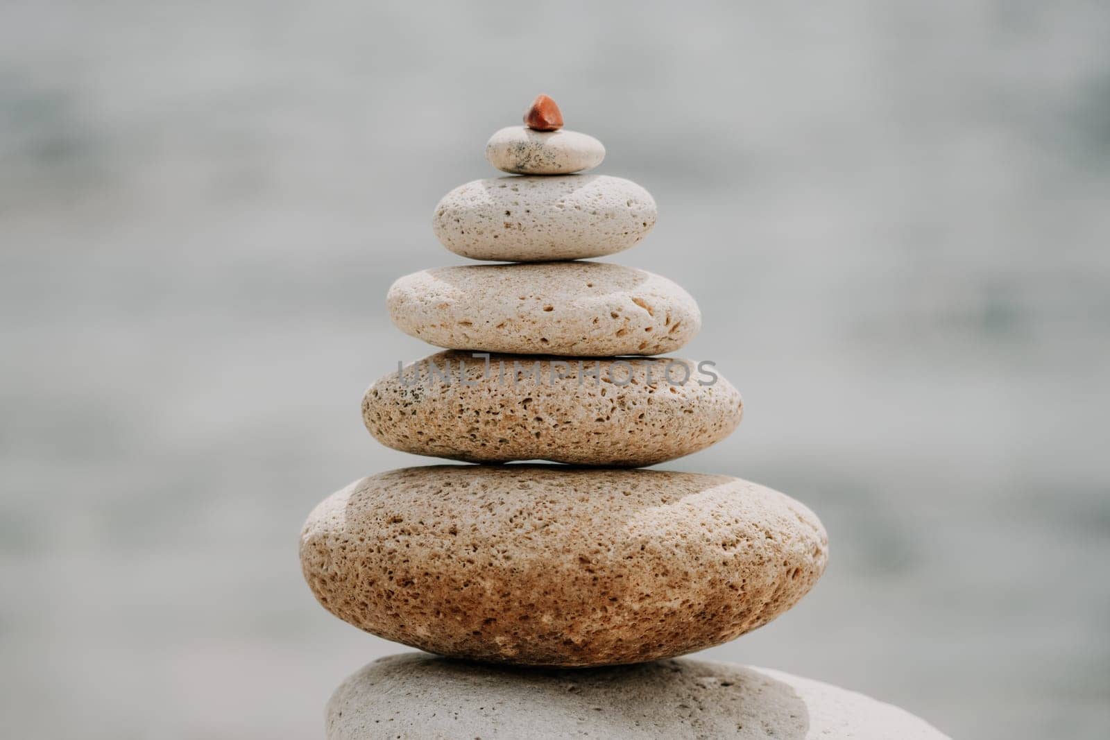 Pyramid stones on the seashore with warm sunset on the sea background. Happy holidays. Pebble beach, calm sea, travel destination. Concept of happy vacation on the sea, meditation, spa, calmness.