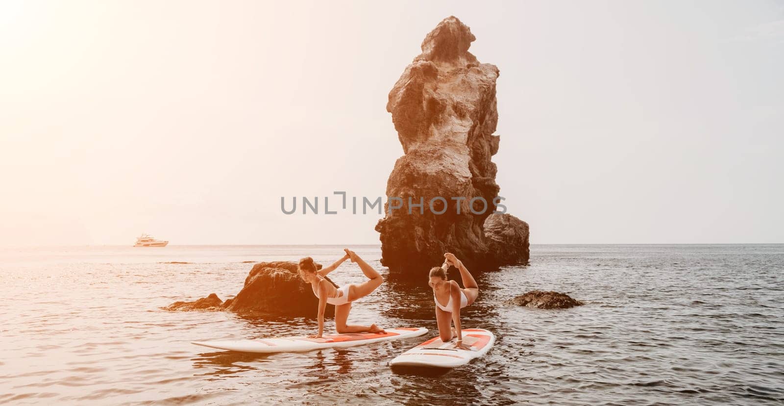 Woman sup yoga. Middle age sporty woman practising yoga pilates on paddle sup surfboard. Female stretching doing workout on sea water. Modern individual hipster outdoor summer sport activity