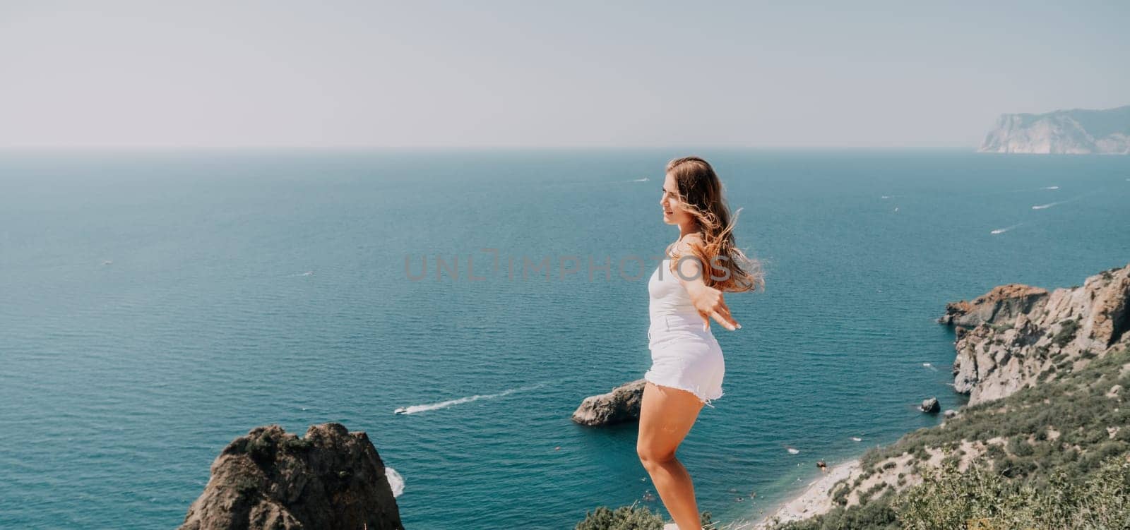 Woman summer travel sea. Happy tourist enjoy taking picture outdoors for memories. Woman traveler posing over sea bay surrounded by volcanic mountains, sharing travel adventure journey by panophotograph