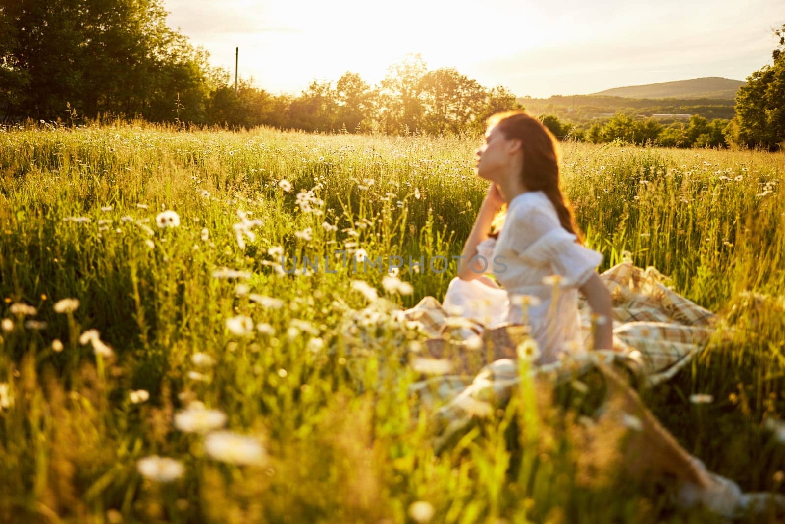 woman sitting in a field with daisies in a light dress out of focus by Vichizh
