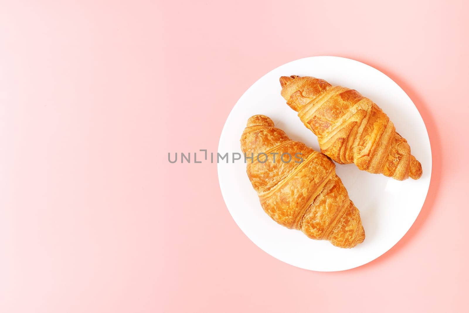 Plate with delicious croissants on a pink background. french pastries. copy space. by lara29