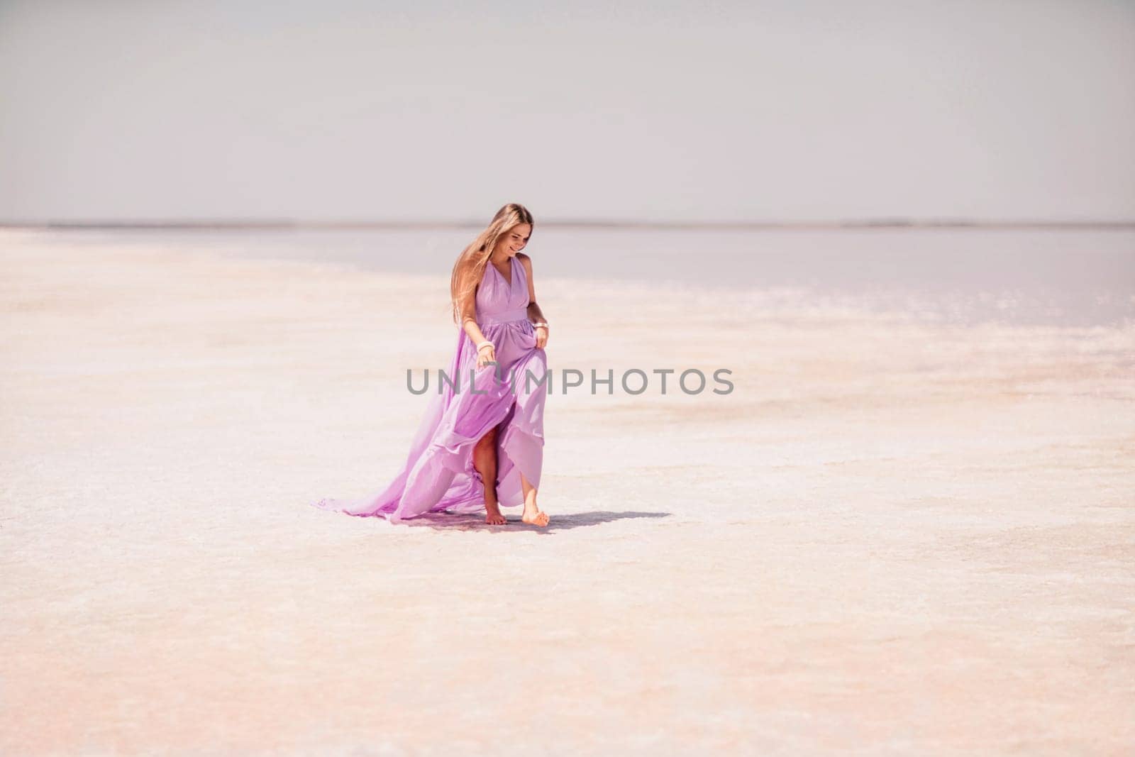 Woman pink salt lake. Against the backdrop of a pink salt lake, a woman in a long pink dress takes a leisurely stroll along the white, salty shore, capturing a wanderlust moment. by Matiunina