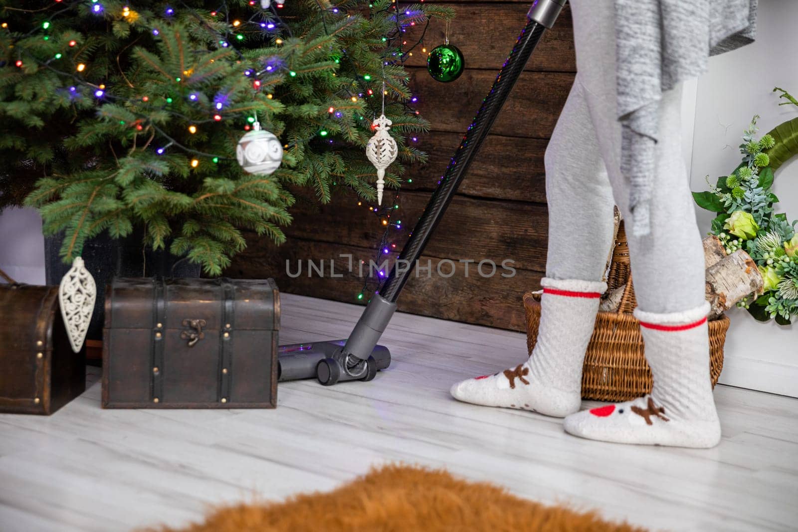 Before Christmas, thorough preparations and cleaning around the house are taking place. Vacuuming under the Christmas tree.