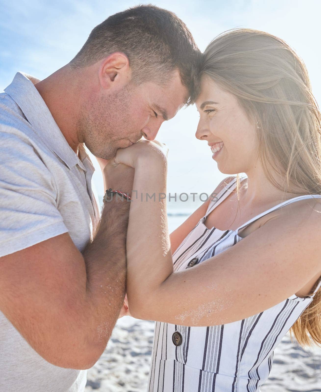 Love, affection and couple with kiss at the beach on a romantic date to relax together in summer. Trust, care and man with gratitude, care and respect for a woman by the ocean on a travel holiday by YuriArcurs