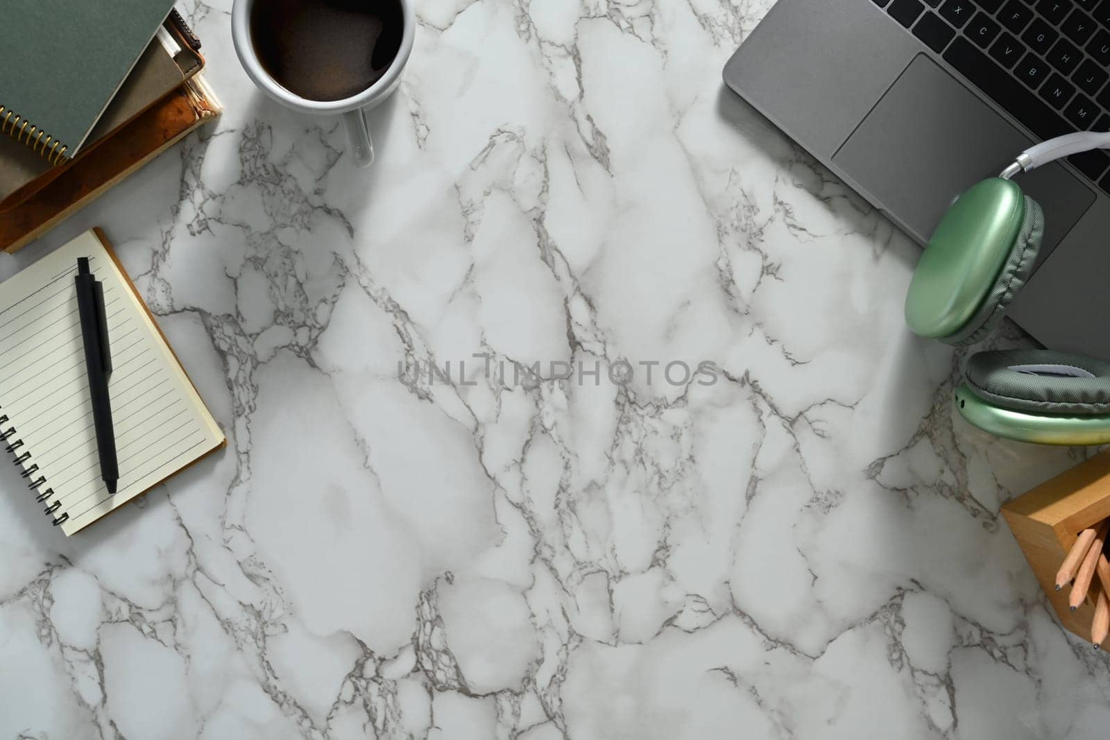 Laptop, headphone, notepad and coffee cup on marble table. Top view with copy space.