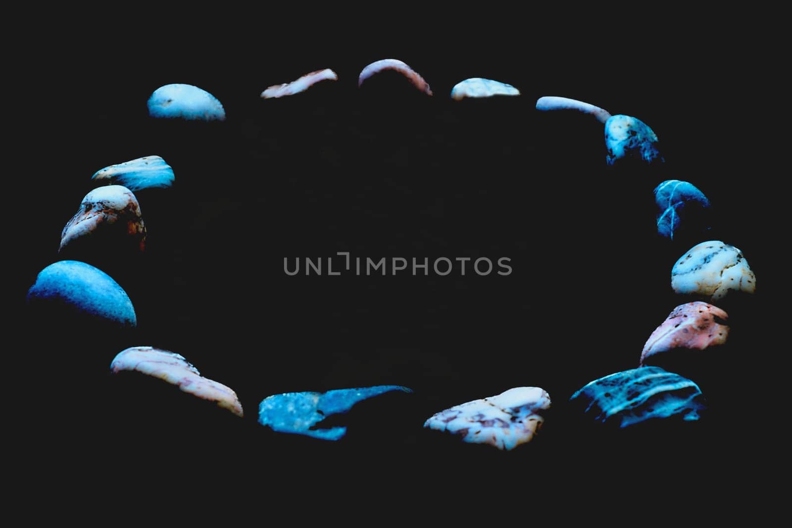 Blurred multicolored stones in blue light in a circle on black by jovani68