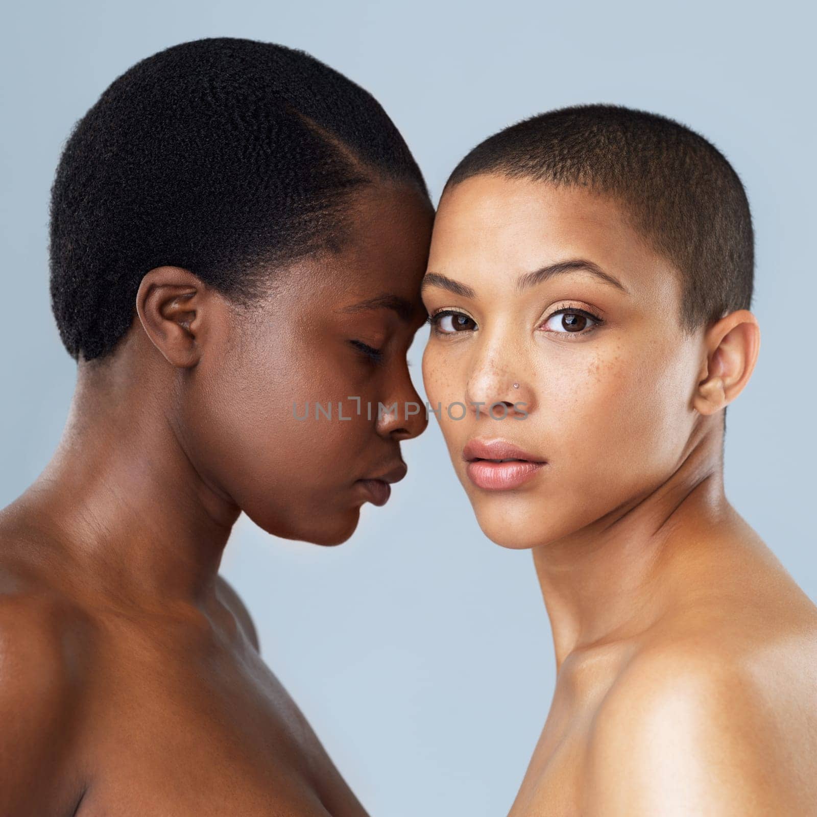 She is everything to me. Portrait of two beautiful young women standing close to each other against a grey background